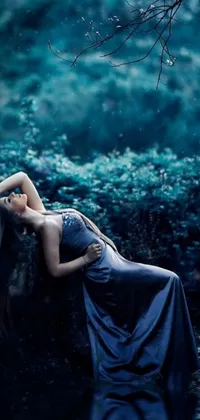 This phone live wallpaper showcases a beautiful woman in a dreamy blue dress laying on a rock