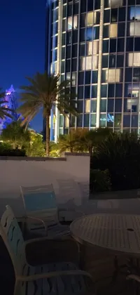 This phone live wallpaper showcases a mesmerizing night scene with a table, chairs, and a building in the backdrop