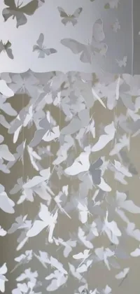 This phone live wallpaper features a stunning design of paper butterflies hanging from a white ceiling