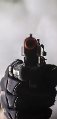 This stunning phone live wallpaper showcases a close up image of a gun being held by a person against a backdrop blanketed in thick fog