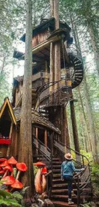This live phone wallpaper shows a man standing near a tree house in lush nature