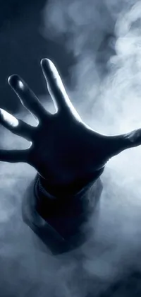 This phone live wallpaper features a haunting close-up of a hand emitting smoke amidst volumetric clouds and mist