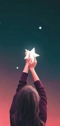 This live wallpaper showcases a dreamy scene of a woman holding a star above her head