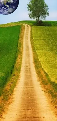 This phone live wallpaper features an earth image over a serene dirt road, surrounded by lush green fields and hilly terrain