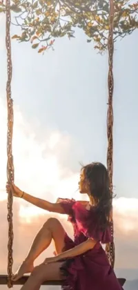This stunning phone live wallpaper features an elegant woman in a beautiful pink dress seated on a swing