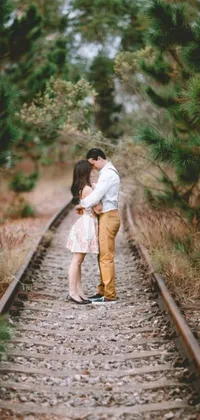 This live wallpaper depicts a romantic scene of a couple locked in a passionate kiss on a train track, situated in the midst of a picturesque forest