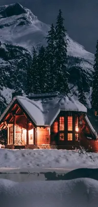 This live wallpaper for your phone features a cozy cabin set against a snowy mountain landscape