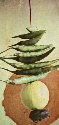 This phone live wallpaper showcases an artistic still life of dangling green beans, inspired by surrealism and mid-century modern collage art