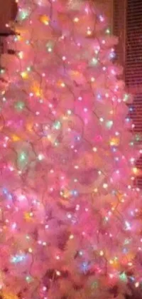 This phone live wallpaper features a white Christmas tree with multi-colored lights that exude winter vibes