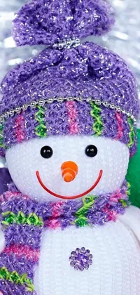 This phone live wallpaper features a snowman adorned with a hat and scarf against a sparkling backdrop of falling white snow