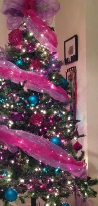 This stunning live wallpaper depicts a Christmas tree adorned with lovely pink and blue ornaments, complemented by elegant purple ribbons