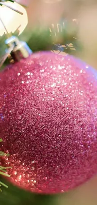 This live wallpaper boasts a pink ornament hanging from a Christmas tree branch