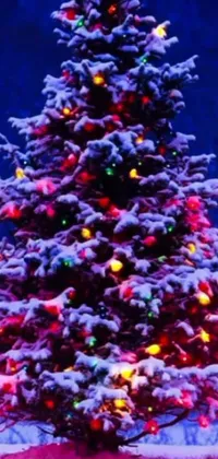 This live wallpaper depicts a luminous Christmas tree amidst a snowy landscape