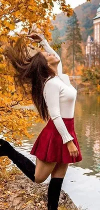 This phone live wallpaper showcases a serene body of water, with a beautiful woman wearing a flowing red skirt that sways in the breeze