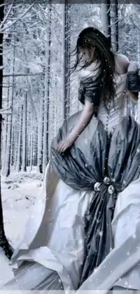 This beautiful phone live wallpaper captures a haunting and dreamy image of a woman walking through a snowy forest landscape