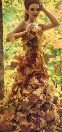This live wallpaper features a breathtaking woman adorned in a dress made of fall foliage, set against an autumn backdrop of colorful maples