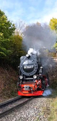 Get mesmerized with this stunning live wallpaper featuring a steam engine locomotive traversing through a picturesque forest during the autumn season