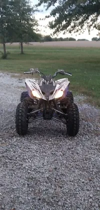 This striking phone live wallpaper features a parked four wheeler on a rural gravel road, with cool purple and gray lighting adding a moody touch