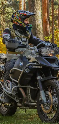 This stunning phone live wallpaper captures the beauty of nature with a man riding a motorcycle through a forest