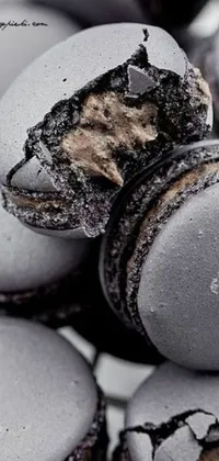 This live wallpaper features a visually stunning pile of macarons photographed up close, with black and grey paint dripping down the sides