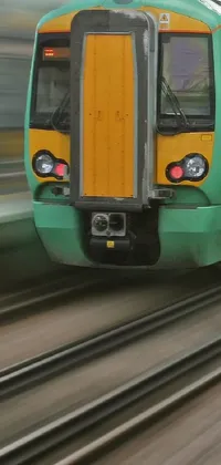 This train live wallpaper features a green and yellow train traveling on train tracks