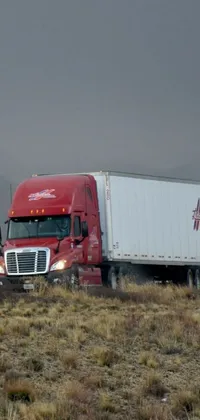This live wallpaper features a red semi-truck driving down a road in the middle of a field under a cloudy sky