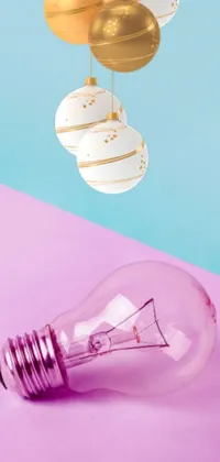 This phone live wallpaper showcases a digital rendering of a light bulb on a pink and blue surface with decorative ornaments in white and gold colors