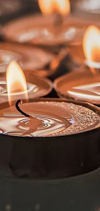 This phone live wallpaper depicts a group of lit candles, framed by a copper table with reflections