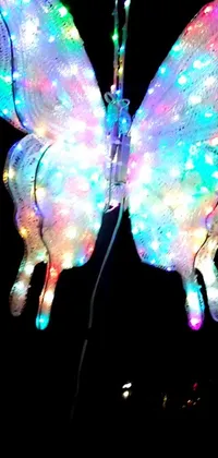This phone live wallpaper features a holographic effect butterfly in vibrant illuminated hues with large LED lights integrated into its wings