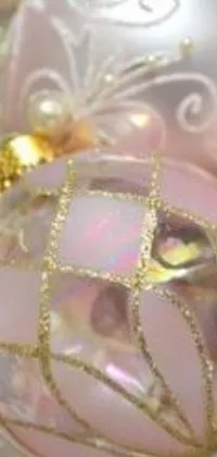 This charming live wallpaper features a close-up of a pink Christmas ornament, along with golden ornaments and glittering snowflakes