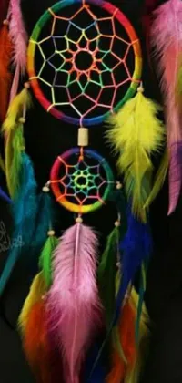 This live wallpaper features a colorful dream catcher, woven with bright threads and adorned with feathers in vibrant hues of red, yellow, blue, green, and purple
