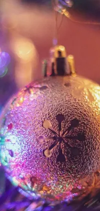 This phone live wallpaper features a beautiful close-up of a Christmas ornament on a tree, with purple and yellow lighting creating a mesmerizing display