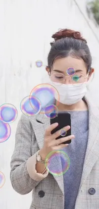 Get this face mask phone live wallpaper for your device! Featuring a woman absorbed in her phone surrounded by playful floating bubbles