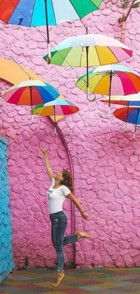 This phone live wallpaper features a vibrant and colorful scene of a woman standing underneath a cluster of umbrellas