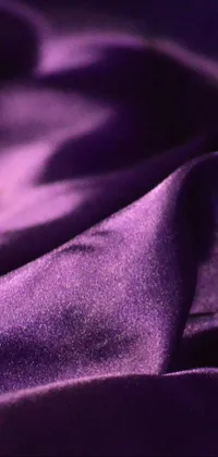 This live phone wallpaper showcases a stunning close-up of a vibrant purple cloth overlaying a bedspread