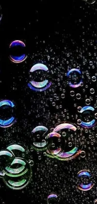 Introduce a stunning live wallpaper with a holographic design featuring a variety of bubbles in different sizes and hues atop a black surface