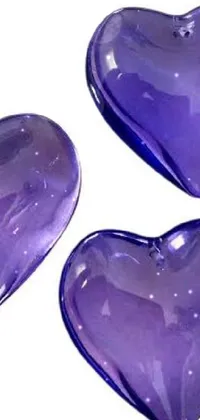 This phone live wallpaper features three purple glass hearts made from sapphire stone set against a white background