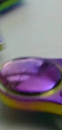 Introducing a stunning live wallpaper featuring a macro photograph of a purple fidget spinner sitting on a table