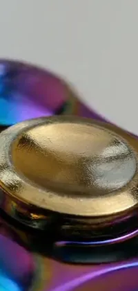 This phone live wallpaper features a captivating macro photograph of a colorful fidgeter on a reflective table