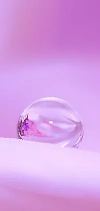 Enhance your smartphone experience with this mesmerizing phone live wallpaper featuring a macro photograph of a water droplet on a crystal-like surface over a pastel purple background