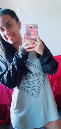 This live wallpaper showcases a woman taking a selfie in front of a mirror while wearing a cozy sweatshirt and t-shirt