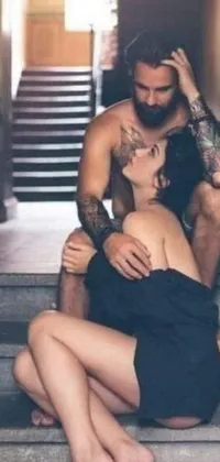 This stunning live wallpaper features a beautiful photograph of a tattooed man and a woman in a loving embrace while sitting on a set of stairs