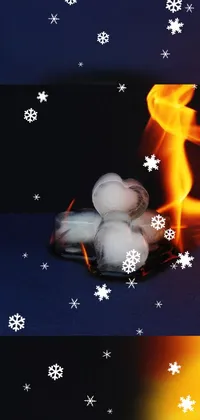 This live wallpaper features a playful scene of snow balls arranged on a table, set against an abstract background image of vibrant orange flames and fire