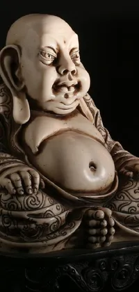 This live phone wallpaper features a beautifully crafted statue of a smiling buddha set against a black background