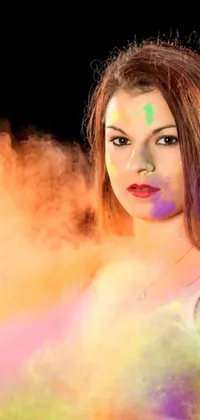 This vibrant live wallpaper showcases a woman with colored powder on her face in front of a backdrop of swirling smoke