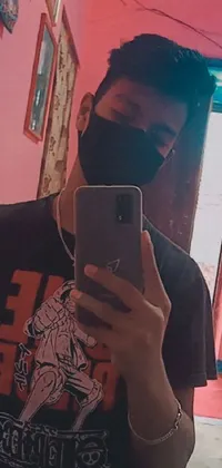 This phone live wallpaper showcases an image of a man wearing a black t-shirt and a black mempo mask, taking a picture of himself in a mirror