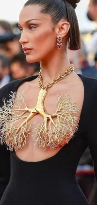 This stunning phone live wallpaper showcases a woman wearing a flowing black dress with a gold tree design on her chest