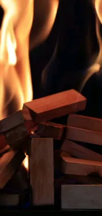 Looking for a visually stunning phone wallpaper for your device? Look no further than this incredible live wallpaper of a burning woodpile! Watch as the flickering, dynamic flames leap and dance amidst the pile of wood, creating an undeniably cozy and inviting atmosphere