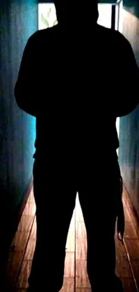 This live phone wallpaper showcases a striking image of a silhouette of a person standing in a dimly lit hallway