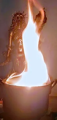 This phone live wallpaper features a mesmerizing image of a burning pot on a table with a cyborg hindu godbody emanating and flowing eerie spiritual energy in the background